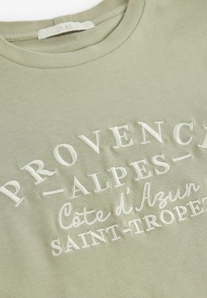 T-shirt en coton vert clair avec un col rond, featuring un texte blanc en relief : "PROVENCE-ALPES-Côte d'Azur SAINT-TROPEZ".