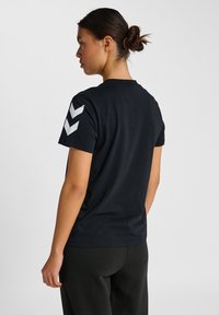 Sort bomuld t-shirt med korte ærmer, der har hvide chevron mønstre på venstre ærme. Enkel crew neck design.