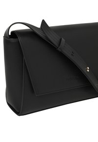 Schwarze Lederhandtasche mit glatter Textur, geometrischem Design und Klappverschluss. Verfügt über einen einzelnen Schulterriemen mit geriffelter Verzierung.