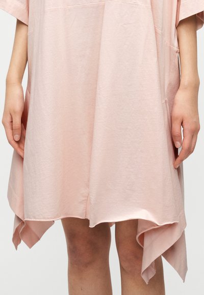 Ροζ, φαρδιά φόρεμα κατασκευασμένο από μαλακό βαμβάκι, με ασύμμετρο τελείωμα και πλαϊνές τσέπες. Ομαλή υφή με μινιμαλιστικό σχεδιασμό.