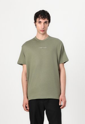 Camiseta de algodón color verde oliva con mangas cortas, cuello redondo, que presenta un texto de logo blanco en el centro del pecho. Textura suave, corte relajado.