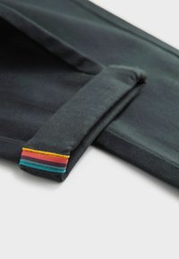 Tummanharmaa kangas, jossa on sileä pinta, jossa on taitettu reuna ja monivärinen raidallinen aksentti punaisena, keltaisena ja tealina.