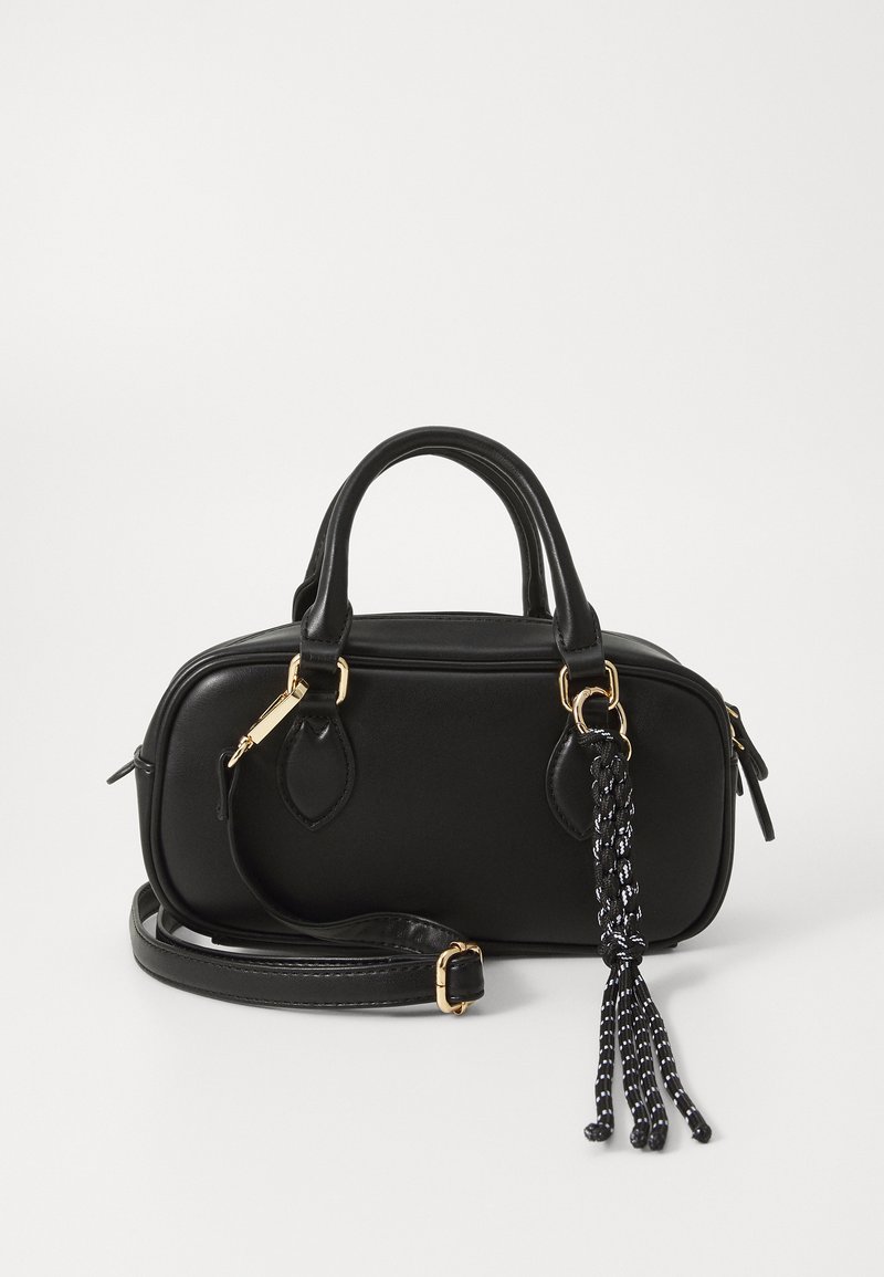 Sac à main en cuir noir avec une forme structurée, deux poignées courtes, une bandoulière amovible et un pompon tressé décoratif. Accents en métal doré.