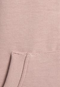 Textura de tela en color rosa claro con un bolsillo acanalado. Material de punto suave con costuras uniformes y sin patrones ni acentos visibles.