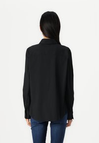 Zwarte longsleeve shirt met een kraag, knoopmanchetten en een licht gebogen zoom, gemaakt van een gladde, effen stof.