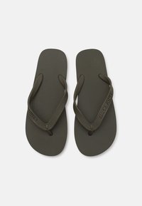 Mørke olivengrønne flip-flops med en struktureret fodseng og tynde stropper, der har mærkenavnet "JACK & JONES" på en strop.