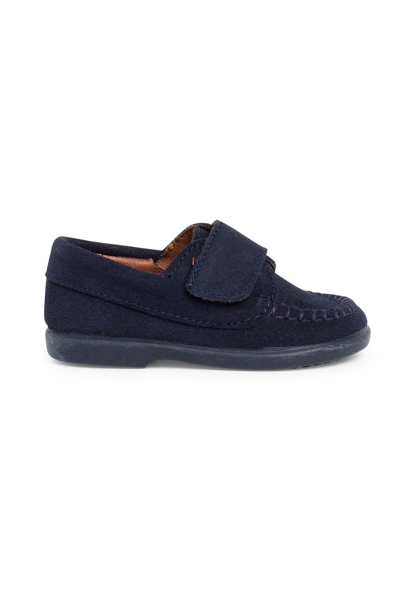 Chaussure en daim marine avec une sangle Velcro, bout arrondi et coutures contrastées. Elle possède une semelle en caoutchouc flexible pour le confort.