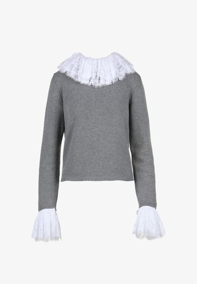 Pilkas megztinis su baltu nėriniu aptrauktu apykakle ir nėriniu išplėstais rankovėmis. Turi trumpą krokuotą siluetą ir banguotą hemą.