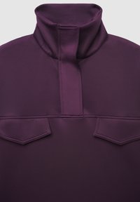 Maglione viola con colletto alto, caratterizzato da una cerniera a metà e due tasche a soffietto frontali. Texture liscia ed elementi di design puliti.