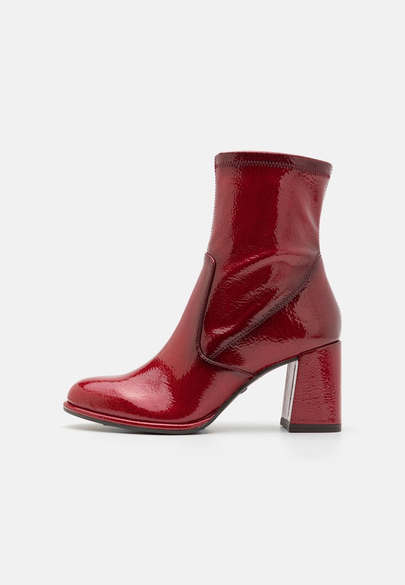 Røde patent lær ankelsko med firkantet tå, mellomhøy chunky hæl og sidepaneldetalj. Glatt, skinnende tekstur med minimal søm.