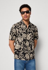 Schwarzes Kurzarm-Hemd mit Knöpfen, das ein beiges botanisches Muster zeigt. Hergestellt aus leichtem Stoff mit lockerer Passform und offenem Kragen.