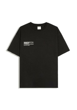 Tricou negru cu mâneci scurte și text alb pe pieptul stâng care spune: „NATURA ADES SERVE CA O ALLEGORIE PUTERNICĂ A ÎNSĂȚI VIEȚII.”