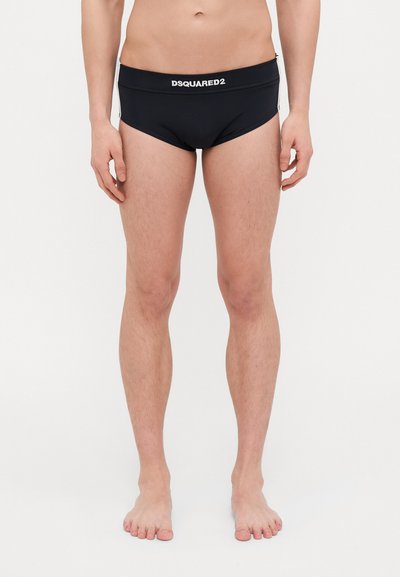 Slip da nuoto neri di DSQUARED2 con una texture liscia e una vita elasticizzata che presenta il nome del marchio in bianco. Design minimalista, forma aderente.