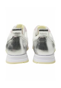 White sneakers with metallic silver heel details and light pink accents. Features a textured heel tab with "NEWD." logo and rubber sole.