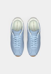 Αθλητικά παπούτσια από γαλάζιο σουέντ με λευκό γιακά, λαστιχένια σόλα, επίπεδες κορδόνια και χρυσές μεταλλικές λεπτομέρειες. Στο εσωτερικό διαθέτουν εκτύπωση λογότυπου.