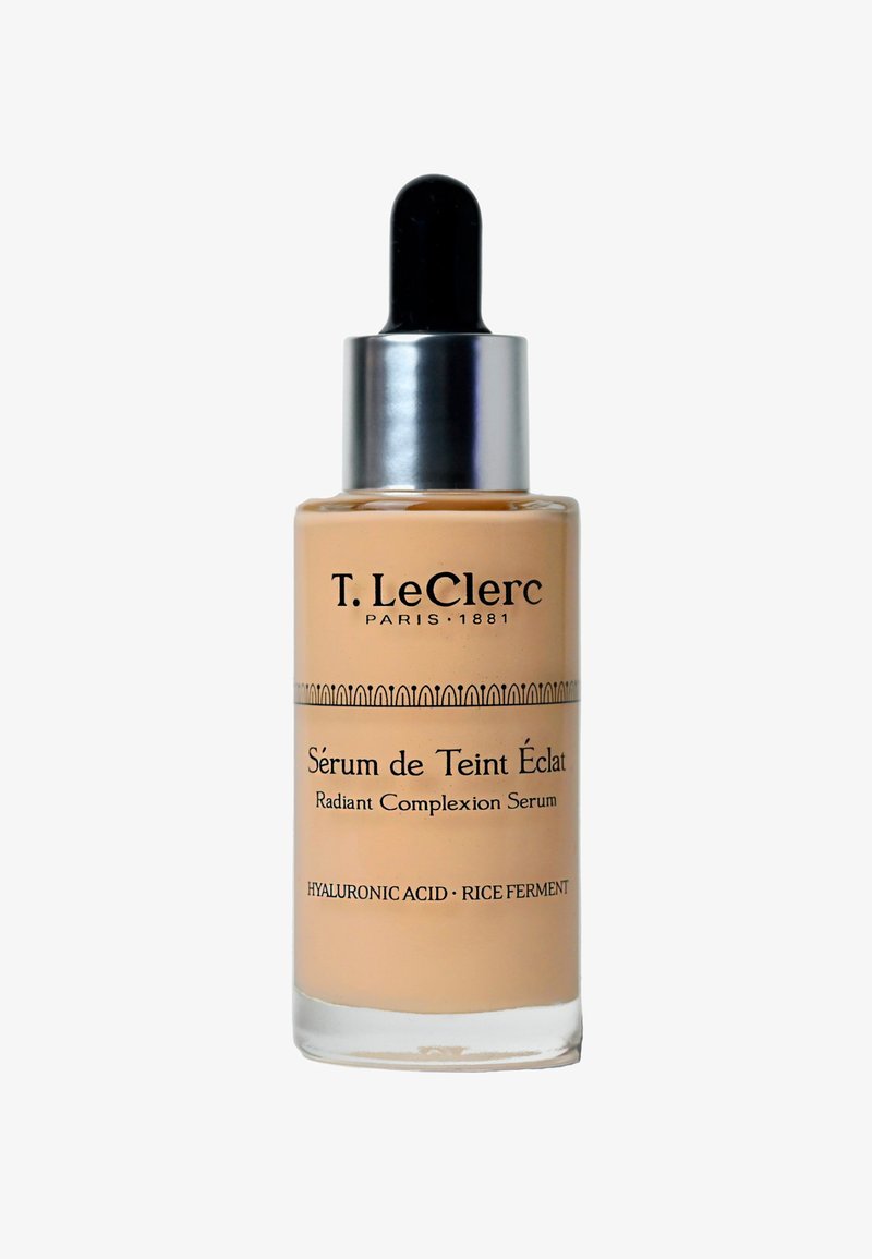 Radiant complexion serum in a transparent glass bottle, featuring a dropper cap. Label has black text on a soft beige background.