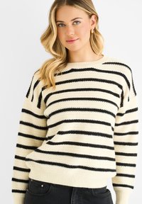 Pullover-Sweater in Creme mit schwarzen horizontalen Streifen, strukturiertem Strickstoff, geripptem Saum und Bündchen. Lockere Passform, runder Halsausschnitt.