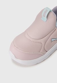 Baskets slip-on Puma rose clair avec semelle blanche et tirette bleue claire, montrant des détails de face et de côté sur fond blanc.