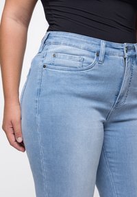 Helle Jeans in Blau mit einer körperbetonten Passform, zwei vorderen Taschen, dezenten Nähten und metallischen Akzenten am Bund.