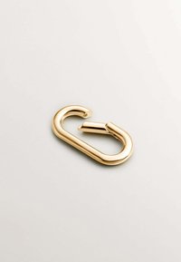 Mosquetón de metal dorado, con forma ovalada alargada y superficie suave y brillante. Cuenta con un mecanismo de cierre seguro y un diseño minimalista.