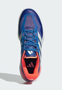 Blue athletic shoe with mesh upper, white stripes, and orange accents. Features a cushioned tongue and textured rubber sole.