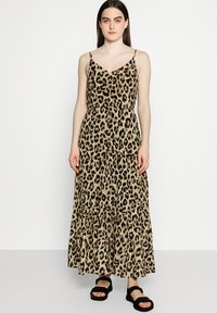 Maxikleid mit Leopardenmuster, dünnen verstellbaren Trägern, V-Ausschnitt, elastischem Bund und gestuften Rock. Kombiniert mit schwarzen Sandalen.