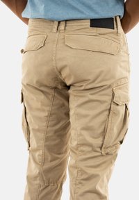 Khaki cargobroek met een aansluitende taille, meerdere zijzakken, zachte stoftextuur en versterkte stiksels langs de naden.