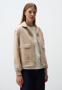 Beige bomberjack met kraag, drukknoopsluiting, twee voorzakken, ribgebreide manchetten en een gladde, gestructureerde stof.
