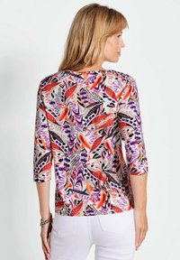 Mehrfarbige Bluse mit 3/4-Ärmeln und einem floralen Muster in Rot, Lila und Schwarz. Hergestellt aus leichtem Stoff mit lockerer Passform.