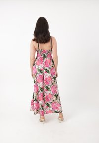 Blomsterlang kjole med sort baggrund og lyser�øde og hvide blomster, spaghetti-stropper og en smocket bodice. Tekstureret stof flyder ned til en flagrende kant.