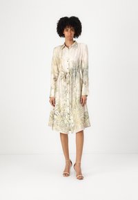 Abito camicia in satin con stampa floreale e palme in toni di verde e beige tenui, con chiusura a bottoni, vita con fiocco e maniche lunghe.