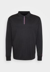 Crna dugouha polo majica s rebrastim ovratnikom, patentnim zatvaračem sprijeda s crvenom, bijelom i plavom prugom te malim logotipom na lijevom manžetnom dijelu.