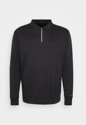 Zwarte longsleeve polo met een geribde kraag, rits aan de voorkant met een rood, wit en blauw streep, en een klein logo op de linkermouw.