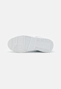 Suela de zapatilla blanca con patrones texturizados y surcos para agarre, que presenta un detalle de logo y un diseño segmentado para tracción.