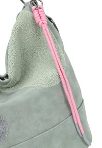 Lichtgroene handtas met textuur, voorzien van een roze trekkoord en metalen ringdetails op een witte achtergrond.