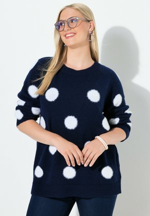 Pull-over bleu marine avec de grands pois blancs, fabriqué dans une matière douce. Doté d'un col rond et de poignets côtelés.