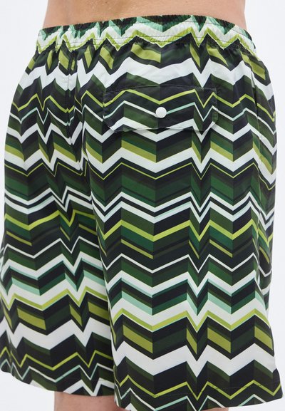 Πράσινο και μαύρο μαγιό-βερμούδα με ζιγκ-ζαγκ σχέδιο, διαθέτει ελαστική μέση και πίσω τσέπη με κούμπωμα κουμπιού.