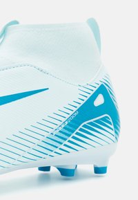 Football boot in light blue and white with a textured upper, featuring sharp blue stripes and a distinctive heel design.