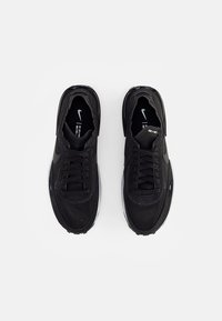 Black sneakers made of fabric and synthetic materials, featuring laces, a cushioned sole, and embossed logo on the side.