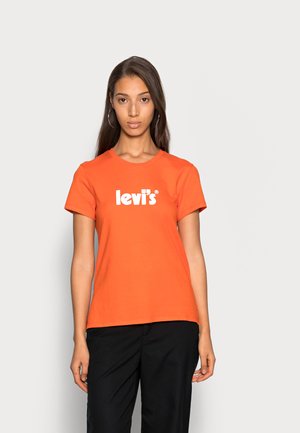 Camiseta de algodón naranja con cuello redondo y mangas cortas, que presenta el logo en blanco de "levi's" centrado en el pecho. Pantalones negros lisos.