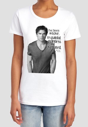 Person wearing a white t-shirt with a black and white photo of a man and text reading "I've been in love. It's painful, pointless and overrated."