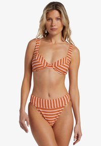 Bikini orange et blanc à rayures avec de larges bretelles, un haut structuré et un bas taille haute. La texture semble lisse et flexible.