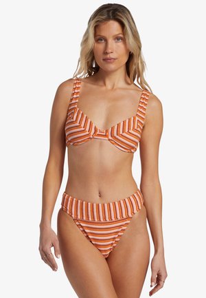 Bikini a strisce arancione e bianche con spalline larghe, un top strutturato e uno slip a vita alta. La consistenza sembra liscia e flessibile.