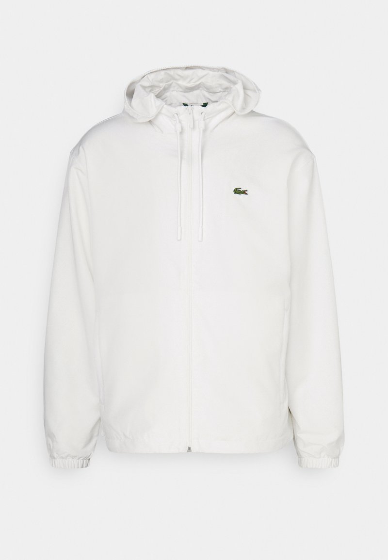 Weißer Zip-Hoodie mit Kapuze, elastischen Bündchen und Kordelzügen. Mit kleinem grünem Lacoste-Logo auf der linken Brust. Angenehme, glatte Textur.