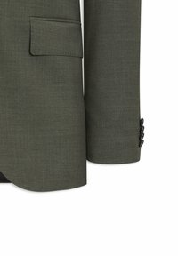 Manche de veste de costume vert olive et bas du corps, avec une poche à rabat et quatre boutons noirs sur le poignet sur fond blanc.
