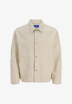 Giacca beige in cotone, con colletto appuntito, bottoni a scatto frontali e due grandi tasche laterali. Texture liscia con vestibilità comoda.