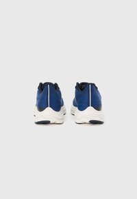 Modré športové topánky s textúrovaným zvrškom, odpruženou podrážkou a kontrastnými bielymi detailmi. Sú vybavené reflexnými prvkami na zadnej časti.