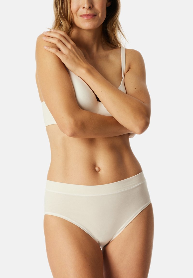 Helle beige nahtlose BH und passende hochtaillierte Slips. Beide verfügen über eine glatte Textur und ein einfaches Design, ohne sichtbare Hardware.