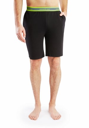 Zwarte katoenen shorts met zijzakken en een groene tailleband met de tekst "slopes & town". Midden bij de dijen lengte, gladde textuur.
