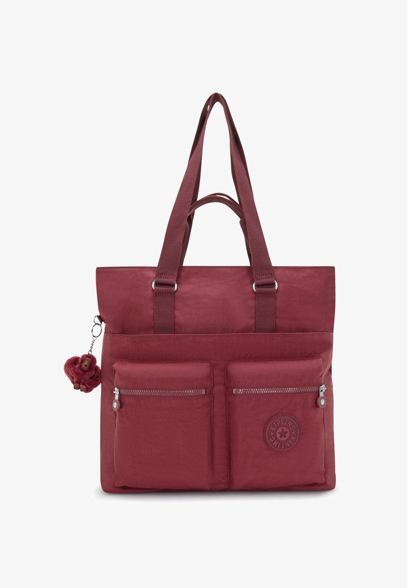 Bordowa torba na ramię z dwoma przednimi kieszeniami na zamek, podwójnymi uchwytami i małym pluszowym breloczkiem w kształcie małpy przypiętym po lewej stronie.